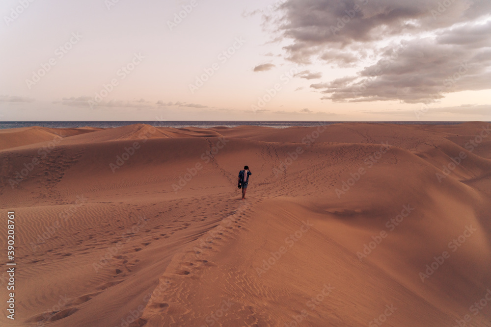 Man walking across sand dunes Man walking across sand dunes