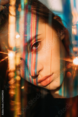 Melancholic young lady among colorful shining ribbons photo