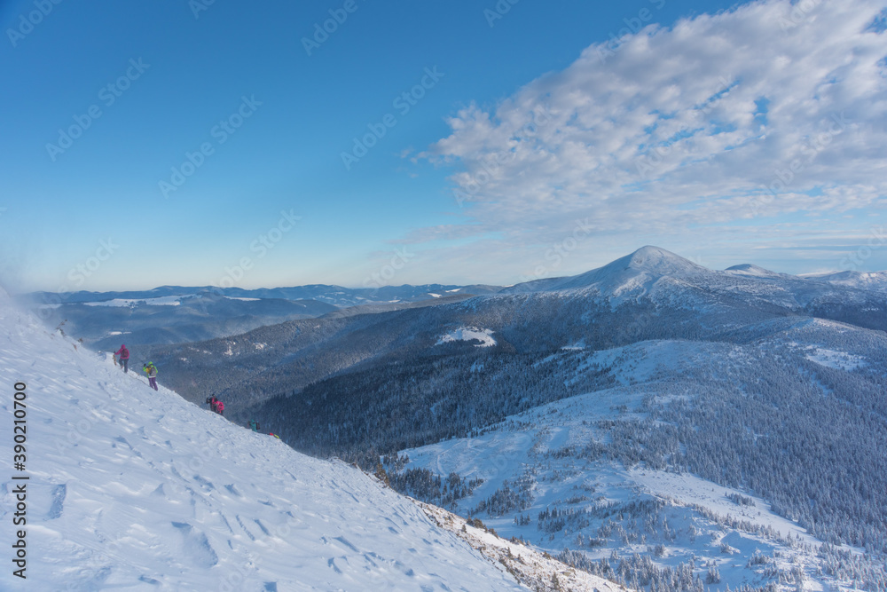 Obraz premium Tourists with a dog travel in a blizzard and bad weather in the mountains