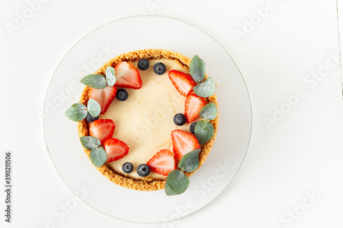 Homemade classic New York cheesecake decorated with fresh strawberries and blueberries on the white background. overhead shot, flat lay