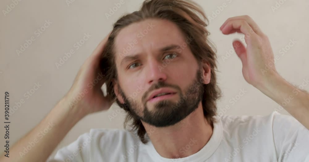 Portrait of bearded young man searching for new pimples on facial skin. Concept of beauty treatment and skin care. Portrait of bearded young man searching for new pimples on facial skin. Concept of beauty treatment and skin care.