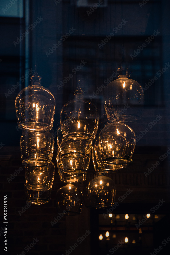 Unusual lamps in the interior of a cafe or restaurant, unusual use of large glasses hanging from the ceiling. Image through the showcase, selective focus