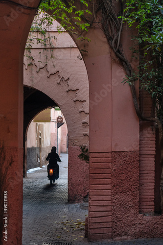 Motorcyclist retreating along narrow road under big arch photo