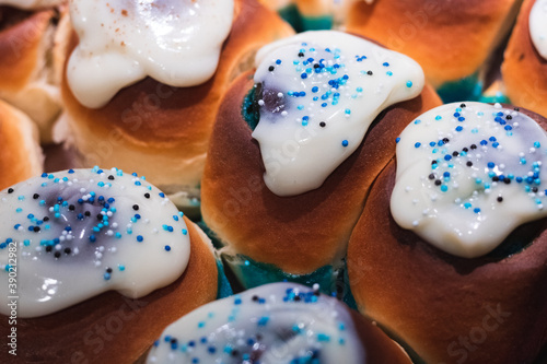 Cinnamon Rolls o Rollitos de Canela caseros rellenos con azúcar de color azul y cubiertos por una capa de glaseado con unas bolitas de azúcar de color azul por encima photo