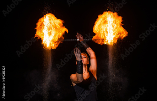 Sensual fire actress manipulate flaming baton in night darkness outdoors, theatre photo
