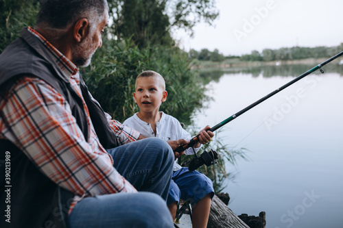 boy fishing with his grandfather by the lake