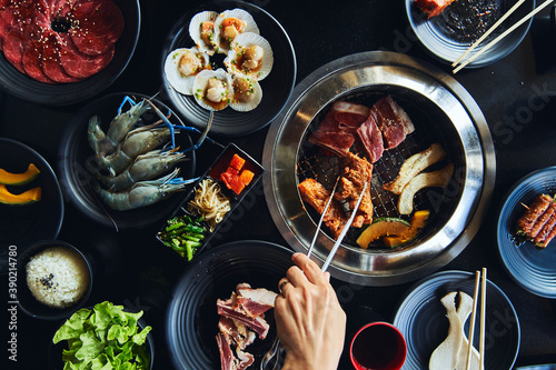 Faceless lady roasting meat with tongs on grill in restaurant photo