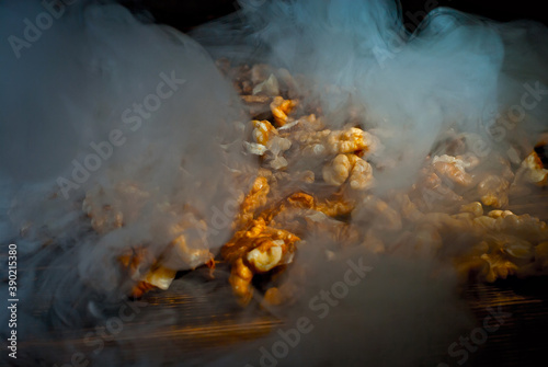 Walnut texture with steam close up. Many halves of peeled nuts on an old wooden board. Food in blue smoke on a background of shabby brown board. Contrasting dramatic light.