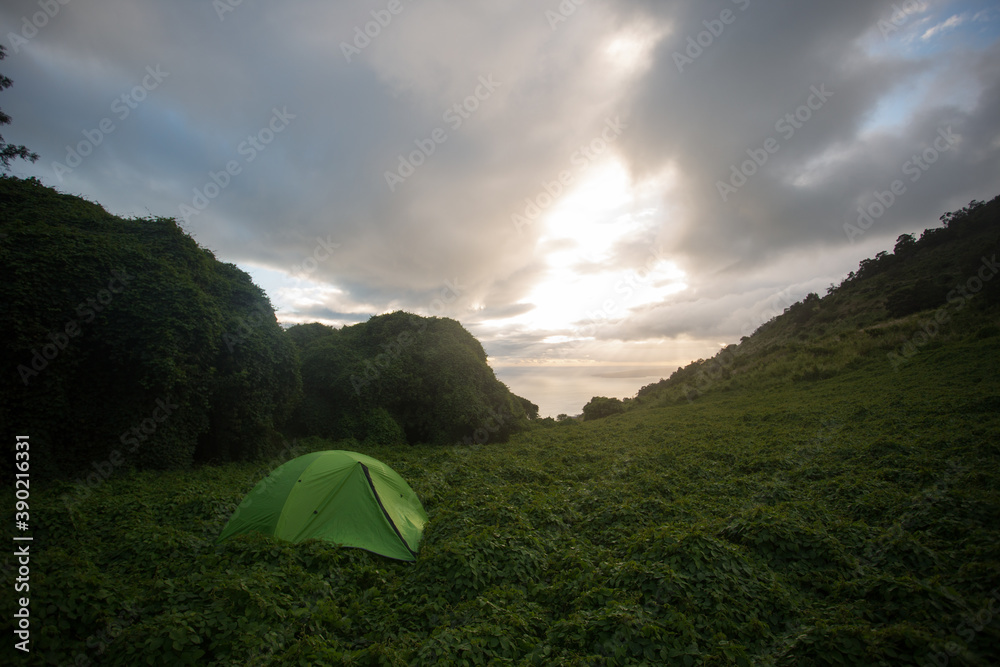 A tent at dawn on a hill overlooking the ocean A tent at dawn on a hill overlooking the ocean
