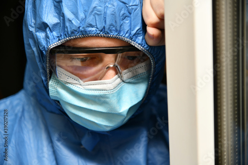Tired doctor, medical worker wearing a protective suit, goggles, and a surgical mask. Health care staff, nurse, high-quality medical care, coronavirus concept.
