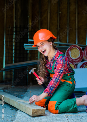 cheerful child laborer using building uniform and hammer tool, working day