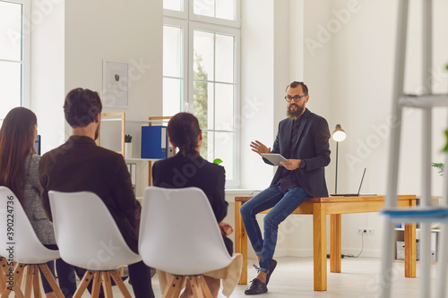 Young businessman speaker or company owner making presentation for office workers photo