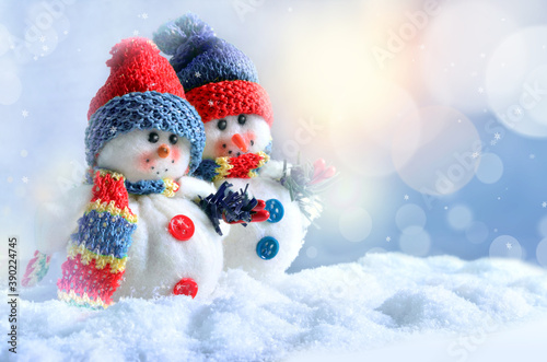 Two funny snowmen in winter on the snow.