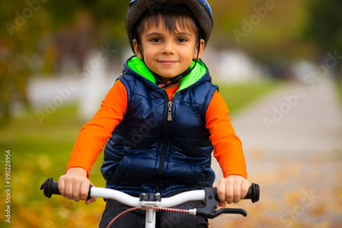 Preschool child posing in a helmet and on a bicycle pedal in the autumn park. Active healthy outdoor sports