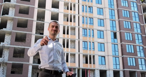 Wallpaper Mural The businessman runs his finger on the tablet and lowers it, looks at the camera smiling and shows the keychain with the key to the apartment. Buy an apartment online. Torontodigital.ca