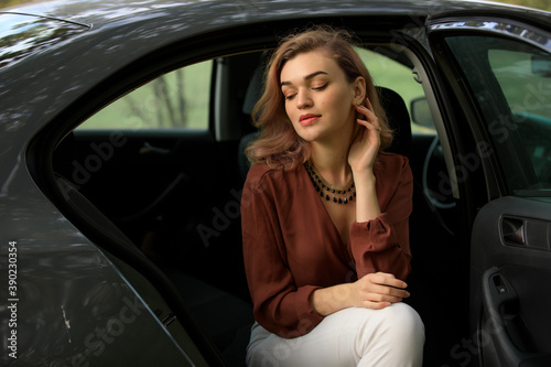 Stylish woman sitting in a grey car in decoration