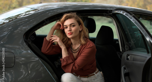 Stylish woman sitting in a grey car in decoration