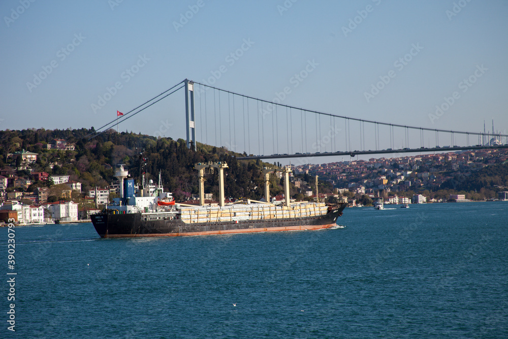 Ship sailing under the Bosphorus Bridge with background of Bosphorus strait on a sunny day with background blue sky and mosque in Istanbul, Turkey. Blue Turkey concept.
