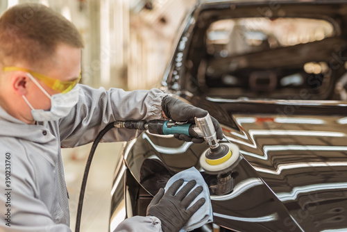 Wallpaper Mural An employee of the car body paint shop with a medical mask on his face polishes the painted surface Torontodigital.ca
