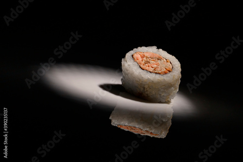 Closeup of a delicious sushi roll under the lights against a dark background