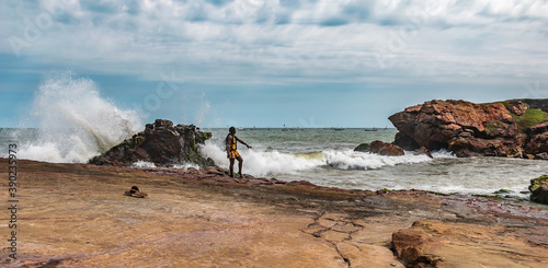 African woman enjoying the waves of the sea at a pebble beach in Accra Ghana West Africa