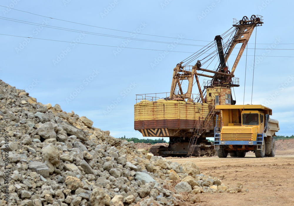 Mining truck and excavators working in the limestone open-pit. Loading and transportation of minerals in the dolomite mining quarry Mining truck and excavators working in the limestone open-pit. Loading and transportation of minerals in the dolomite mining quarry