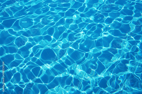 Beautiful pool with sun glare and reflections on the surface of clear and clear water reflecting on a blue bottom.