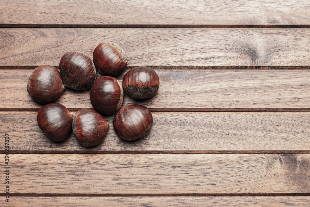 Obraz premium Chestnuts on wooden background, flat lay with copy space
