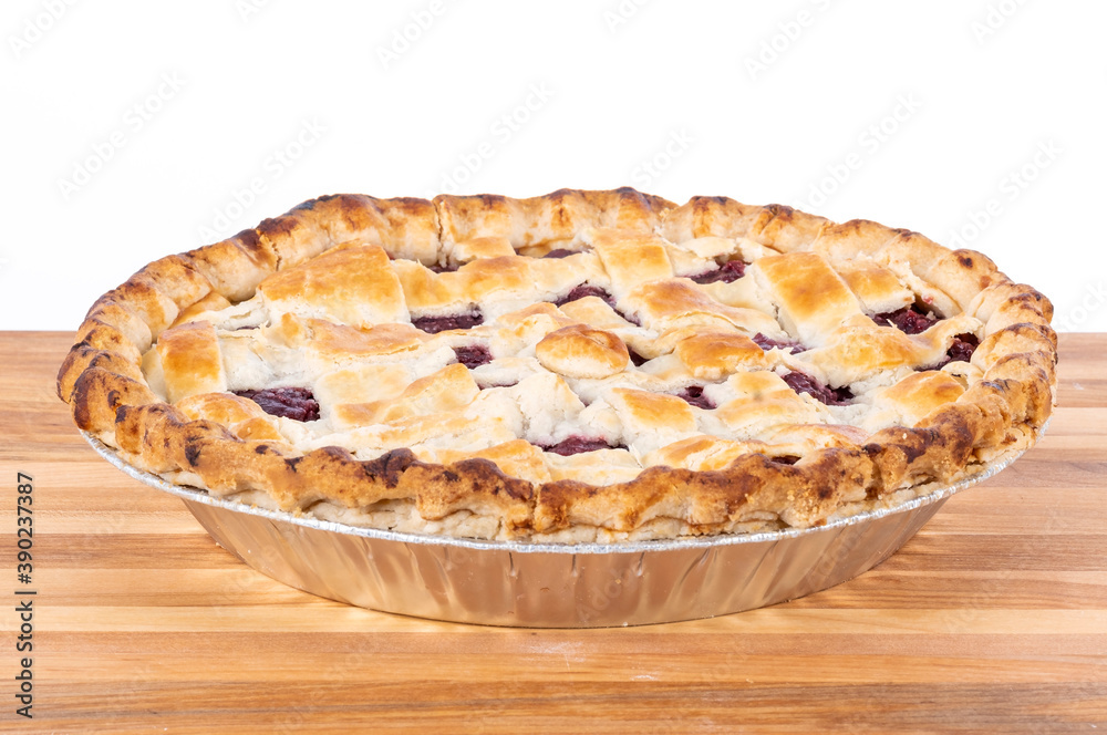 Cooked Cherry Pie in a Foil Plate on a Wood Cutting Board Isolated on White Background Cooked Cherry Pie in a Foil Plate on a Wood Cutting Board Isolated on White Background