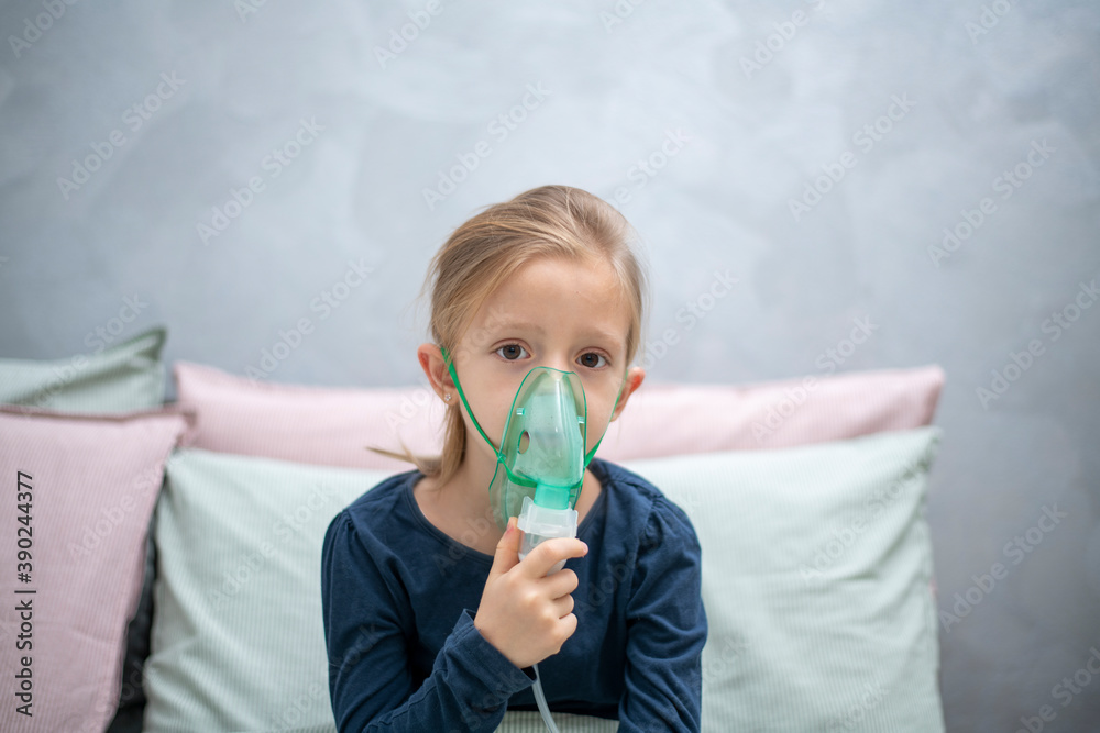 inhalation, aerosol, a 6-year-old girl does inhalation in the bedroom against a gray wall
