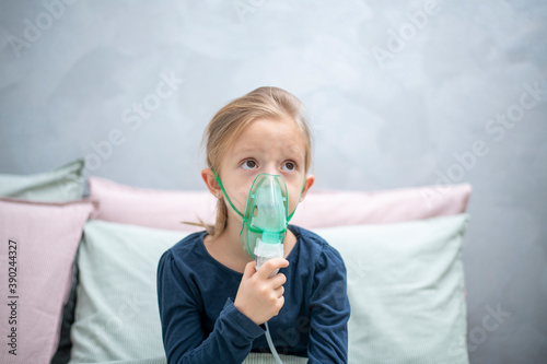 inhalation, aerosol, a 6-year-old girl does inhalation in the beinhalation, aerosol, a 6-year-old girl does inhalation in the bedroom against a gray wall
