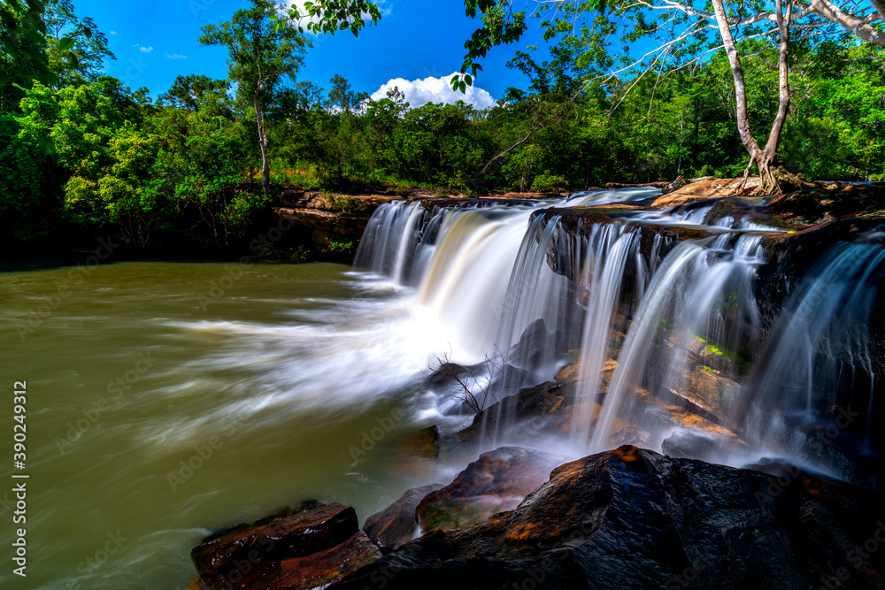 Obraz premium A small waterfall in the deep forest of the border of Thailand and Cambodia,Wang Yai waterfall in tropical forest,Sisaket province,Thailand. Leaf moving low speed shutter blur.