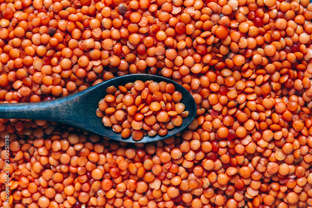 Wooden spoon in red lentils, food background