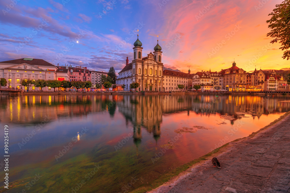 Amazing sunset with colorful clouds in city downtown of Lucerne in Central Switzerland. Jesuitenkirche or Jesuit Church of St. Francis Xavier reflecting on Reuss river of Lucerne's historical city.