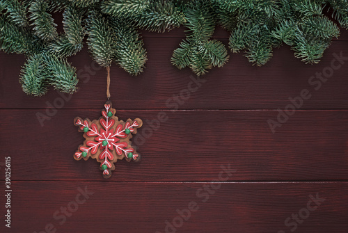 Classic snowflake shaped holiday ornament and spruce tree border on brown wooden background