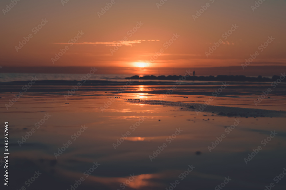 Sunset over wet sand reflecting the golden rays of the sun