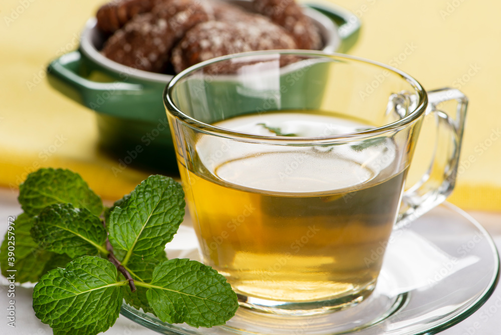 a cup of mint tea with some sweet cookies in the background a cup of mint tea with some sweet cookies in the background