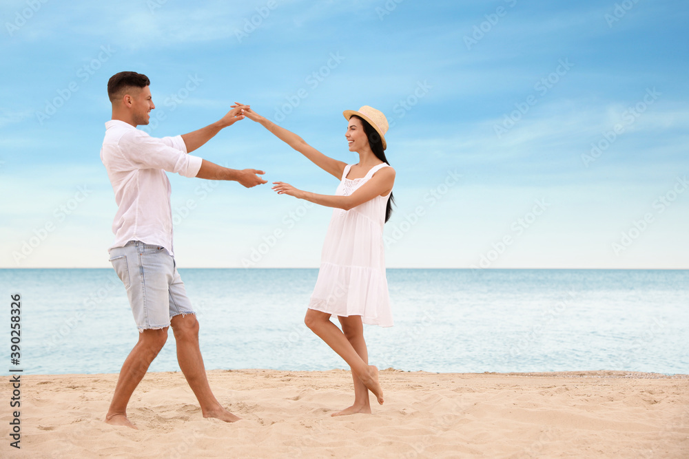 Lovely couple dancing on beach near sea