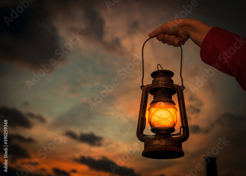 Female's hand holding a lantern with the beautiful sunset in the background photo