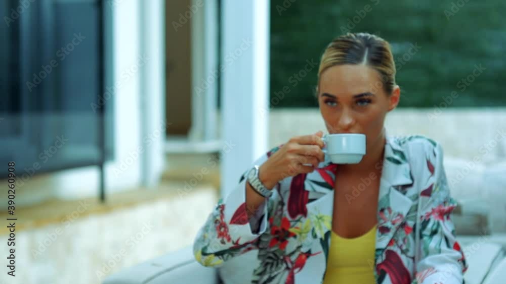 Woman sitting on the balcony takes her coffee cup from the table and sips. Woman sitting on the balcony takes her coffee cup from the table and sips.