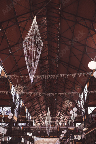 The central market in Budapest decorated for Christmas. Central Market Hall in Hungary. Hall with customers and decorations for Christmas time. It was designed and built by Samu Pecz around 1896.