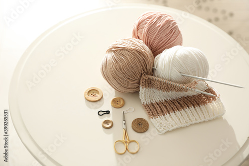 Fotografie Yarn balls and knitting accessories on white table