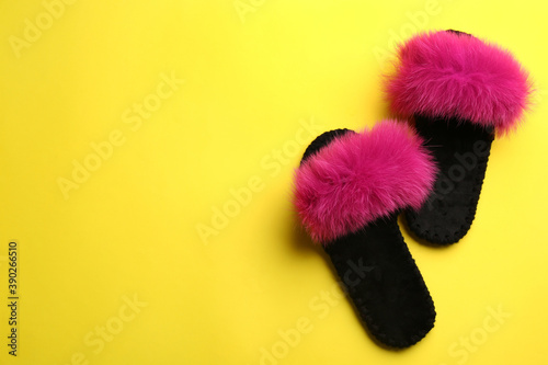 Pair of soft slippers on yellow background, flat lay. Space for text