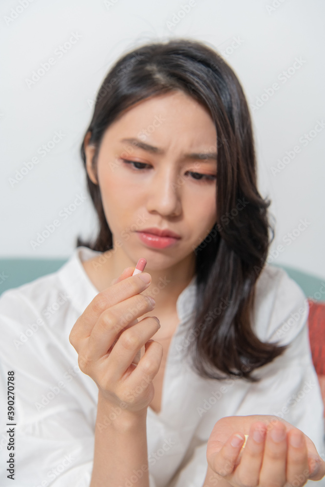 Young Asian woman is taking medicine in living room, taking of necessary medicines safer (Medicine is in focus, people are blurred) Young Asian woman is taking medicine in living room, taking of necessary medicines safer (Medicine is in focus, people are blurred)