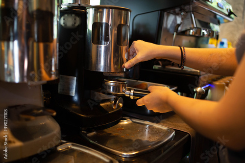 A woman's hand is using a freshly brewed coffee machine to serve the customers in the coffee shop.