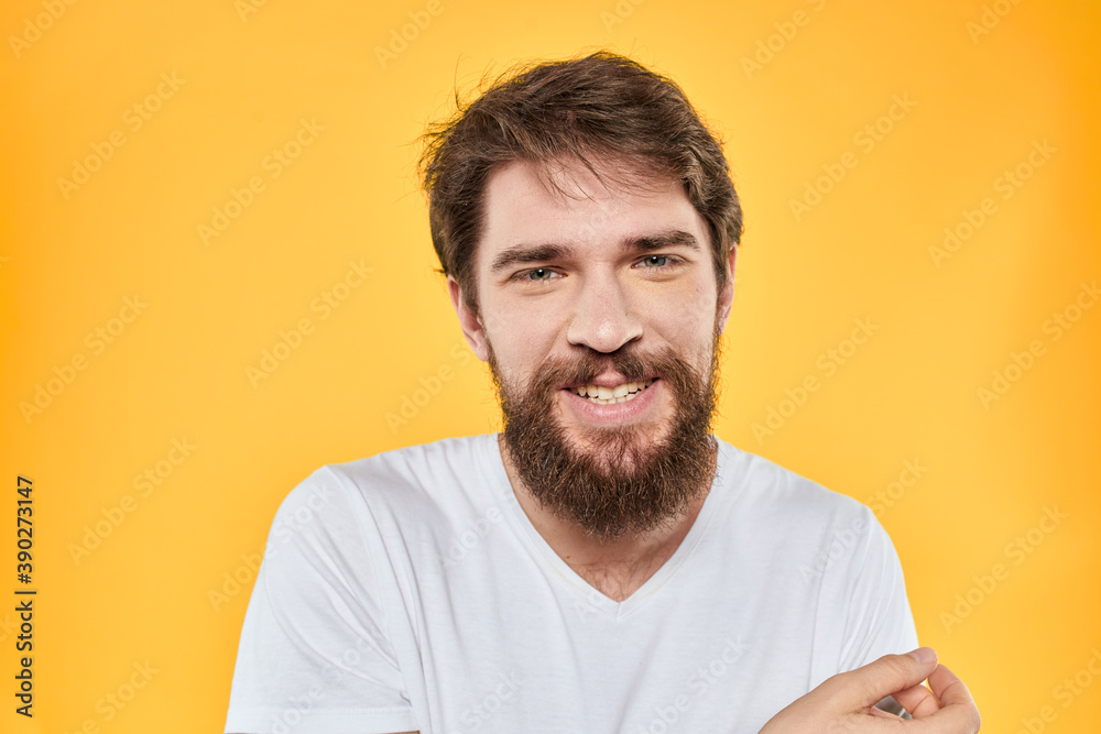 Obraz premium Man with emotional expression white t-shirt close-up studio yellow background