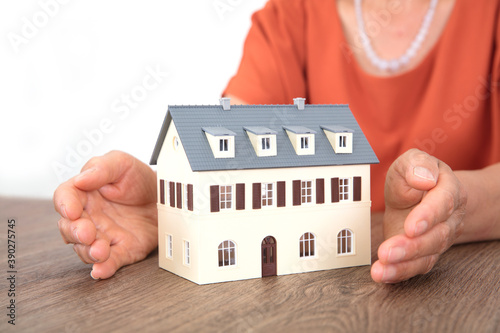The old man's hands caring for the small house model on the table