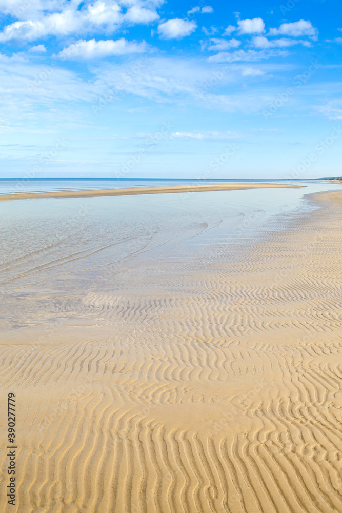 Dzintari Beach, Jurmala, Latvia. Sunny day. Wavy sand on the beach, sea and blue sky with clouds.