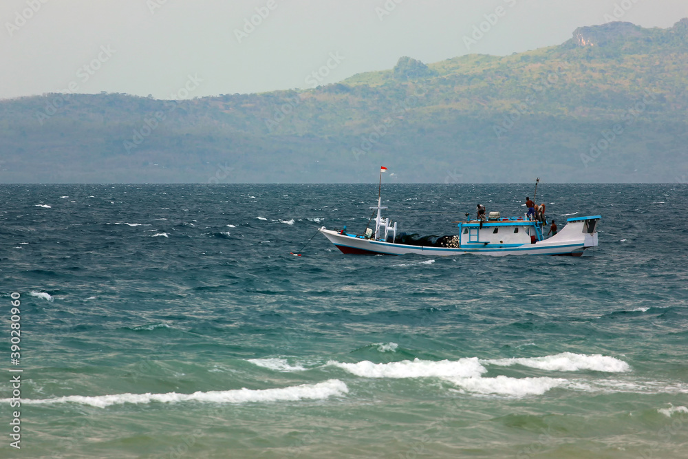 A traditional boat that is operated as public transportation is sailing on a bumpy sea. East Nusa Tenggara - Indonesia
