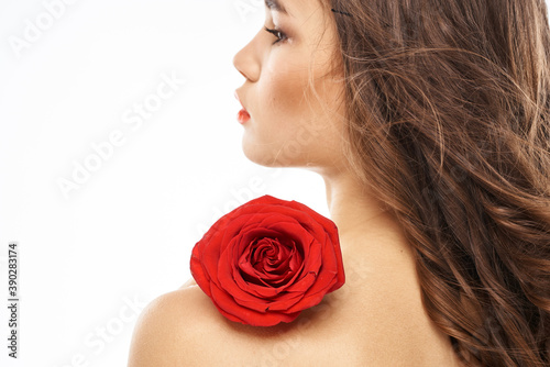 Woman with naked shoulders and red rose evening makeup light background